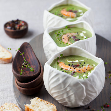 Broccoli, spinach cream soup with shrimp in a white bowls on a wooden board