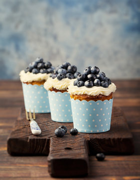 Pumpkin cupcakes decorated with cream cheese frosting and fresh blueberries Copy space