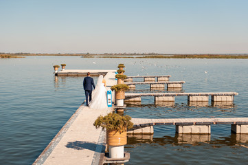 Obraz premium newlyweds is running with joined hands on pier