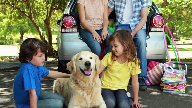 Family with dog next to car