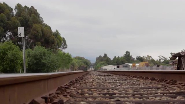 Slow camera dolly of train tracks down the horizon with trees
