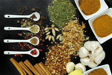 Obraz na płótnie Canvas Set of spices and seasonings with white spoons on black