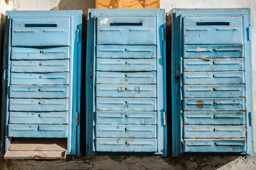 Old retro vintage blue metal mailboxes for letters and newspapers hanging on the wall of an apartment house