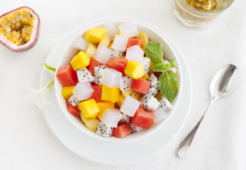 Bowl of fresh exotic fruit salad on white summer background Healthy breakfast Top view