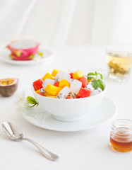 Obraz na płótnie Canvas Bowl of fresh exotic fruit salad on white summer background Healthy breakfast