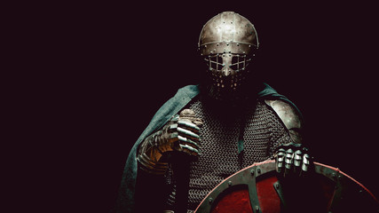 Medieval knight in the armor with the sword and shield.