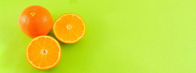 Whole and sliced orange on green background