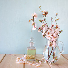 fresh vintage perfume bottle next to white spring flowers on wooden table

