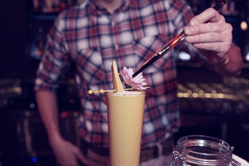 Bartender is decorating a cocktail with mango