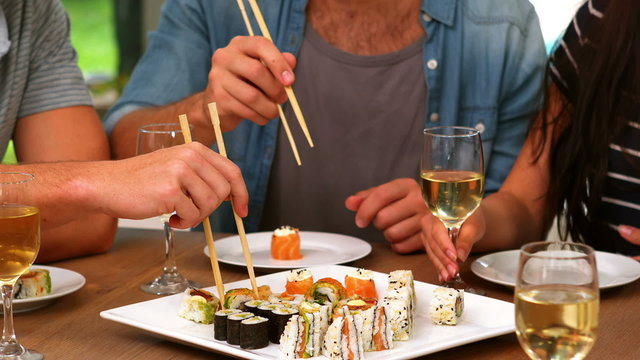 Happy friends eating sushi