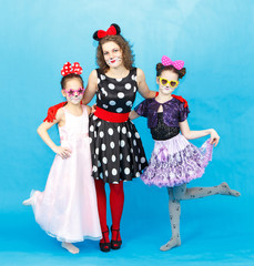 Glamour woman and two girls in party costumes on blue background