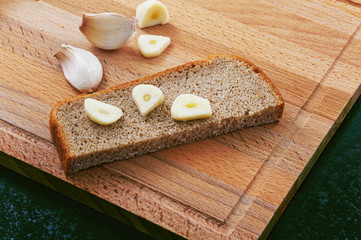 Pieces of black bread and garlic on a cutting board