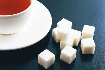 Cup of tea and lump sugar on blue background