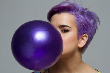 Naklejka premium Closeup of violet short-haired woman holding a balloon with her