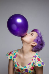 Naklejka premium Violet short-haired woman holding a balloon with her mouth, look