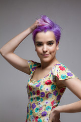 Fototapeta premium Short-haired woman holding her violet hair with one hand.