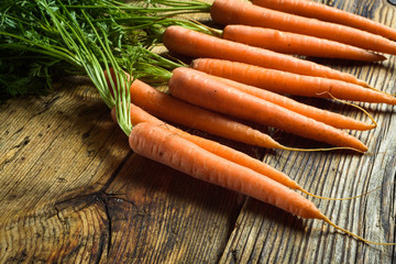 Juicy bunch of carrots on a rustic wooden table.
