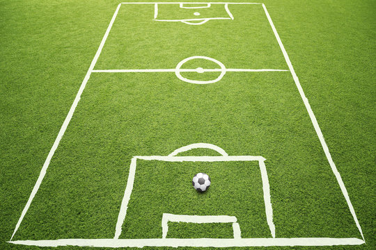 Beautiful sketched soccer field with soccer ball on sunny grass background.
