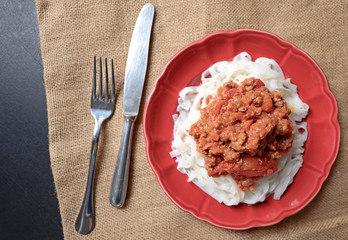 Italian spaghetti on red plate on table