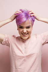 Violet-short-haired woman in pink pastel.holding her hair with t