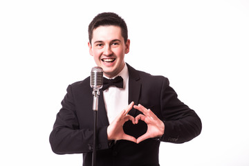 young man in suit singing with the microphone and make love sign with hands. Isolated on white...