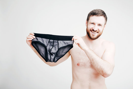 Young attractive bearded naked man holding briefs