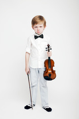 Little cute red-haired boy with a violin in his hands