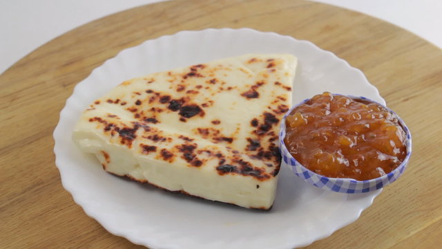Lapland cheese with berry sauce on a white plate on a wooden board