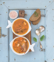 French Bouillabaisse fish tomato soup with salmon fillet, shrimp and spices on rustic wooden board...