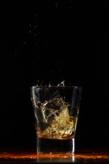 Whiskey splash in glass on black