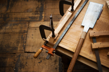 Woodworking. Wood working project on work bench, in a workshop with wooden floor. Clamped pieces of wood with c-clamps and bar clamp. shot in low key and shallow depth of field.