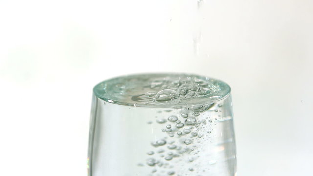 Water pouring into a glass overflowing