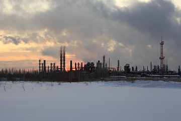 Obraz premium Refinery at sunset sky background. Frosty snowy winter evening.
