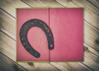Symbol Of Luck. Old  Rusty Horseshoe And Red Book On Wooden Boards. Lucky Concept.