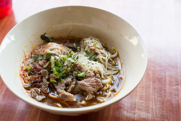 Bowl of noodles with vegetables on wooden table. delicious noodle. hot and sour soup original thai food. Tom Yum