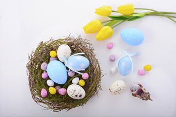 Easter eggs in nest on white wood table.