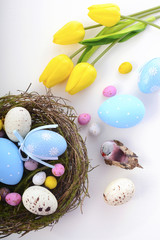 Easter eggs in nest on white wood table.