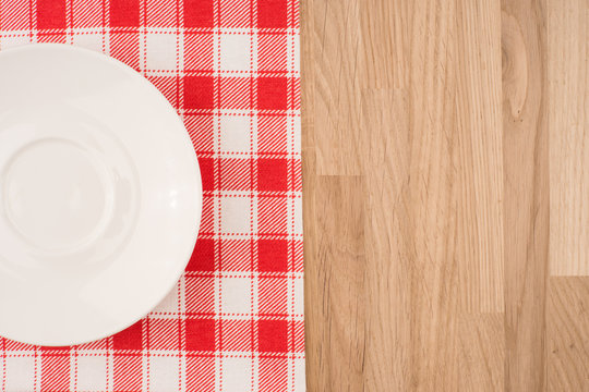 Empty plate on wooden tabletop with tablecloth