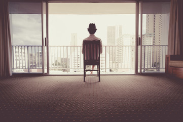 椅子に座って窓から景色を眺める男性