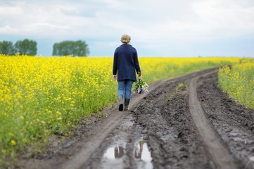 Woman walking along the road with a bouquet of lilacs.