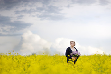 A woman in a flower field with a bouquet.