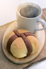 Bread and hot coffee on wooden coaster.