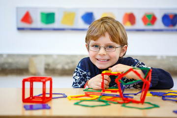 Little kid boy building geometric figures with plastic blocks