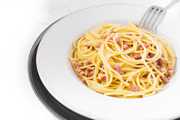 Pasta Carbonara on white plate with parmesan, selective focus.