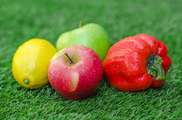 Healthy vegetarian food: the composition of fruits and vegetables in the background of green grass