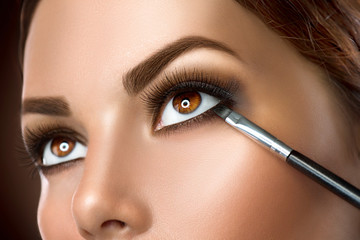Woman applying makeup closeup. Eyeliner