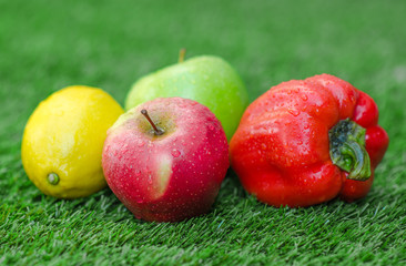 Healthy vegetarian food: the composition of fruits and vegetables in the background of green grass