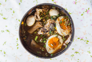 Bowl of noodles with vegetables and soft boiled egg on wooden ta