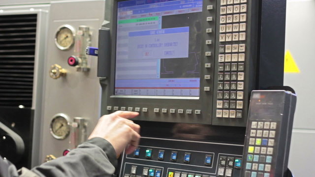 Male Engineer Operating CNC Machinery On Factory Floor
