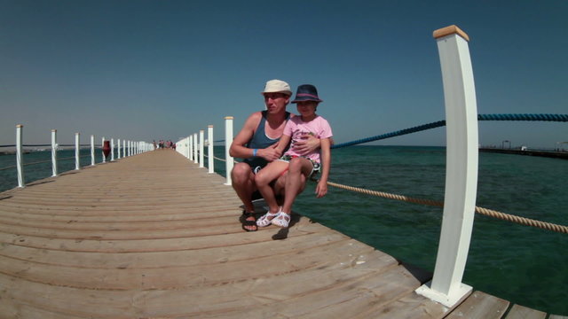 Father embracing his young daughter and pointing while standing at sea pier, Hurghada, Egypt
